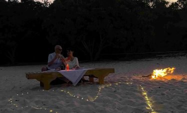 Bonfire dinner experience on a white sand beach in Labuan Bajo during sunset