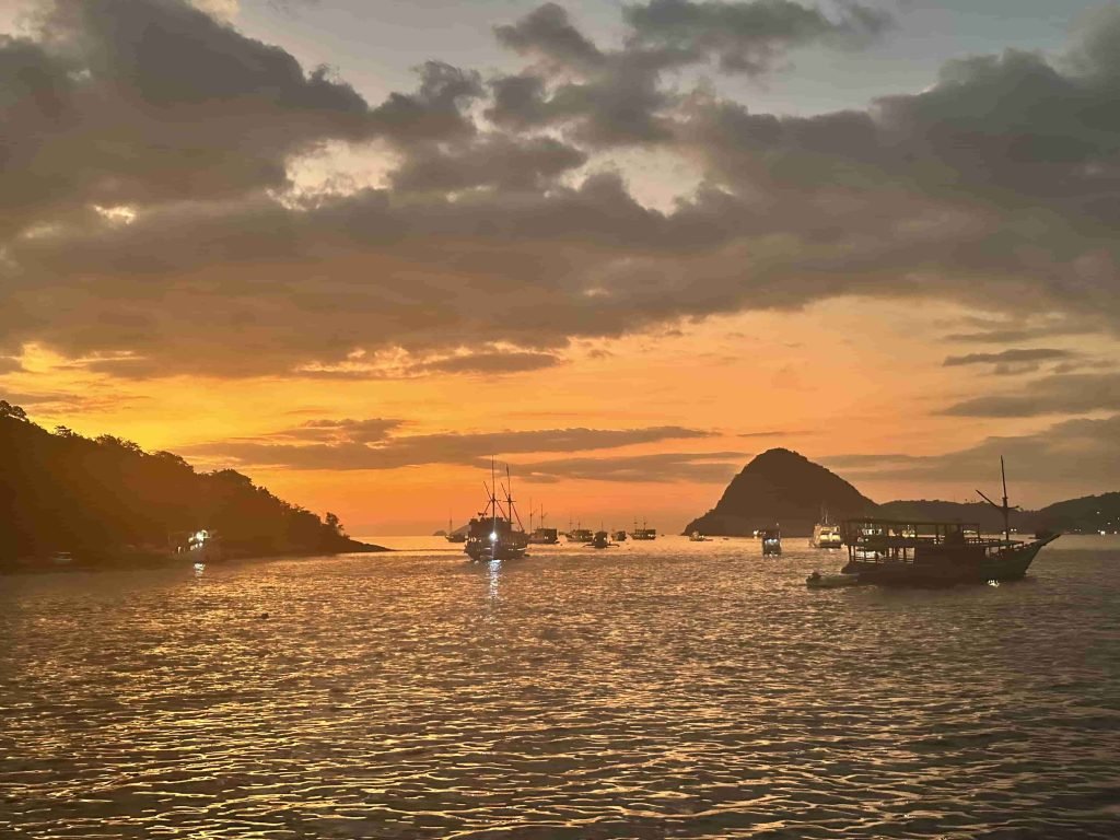 Golden sunset over the horizon with a traditional boat in Labuan Bajo waters