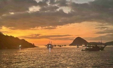 Golden sunset over the horizon with a traditional boat in Labuan Bajo waters