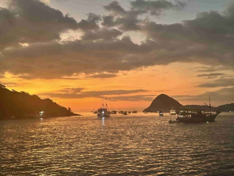 Golden sunset over the horizon with a traditional boat in Labuan Bajo waters