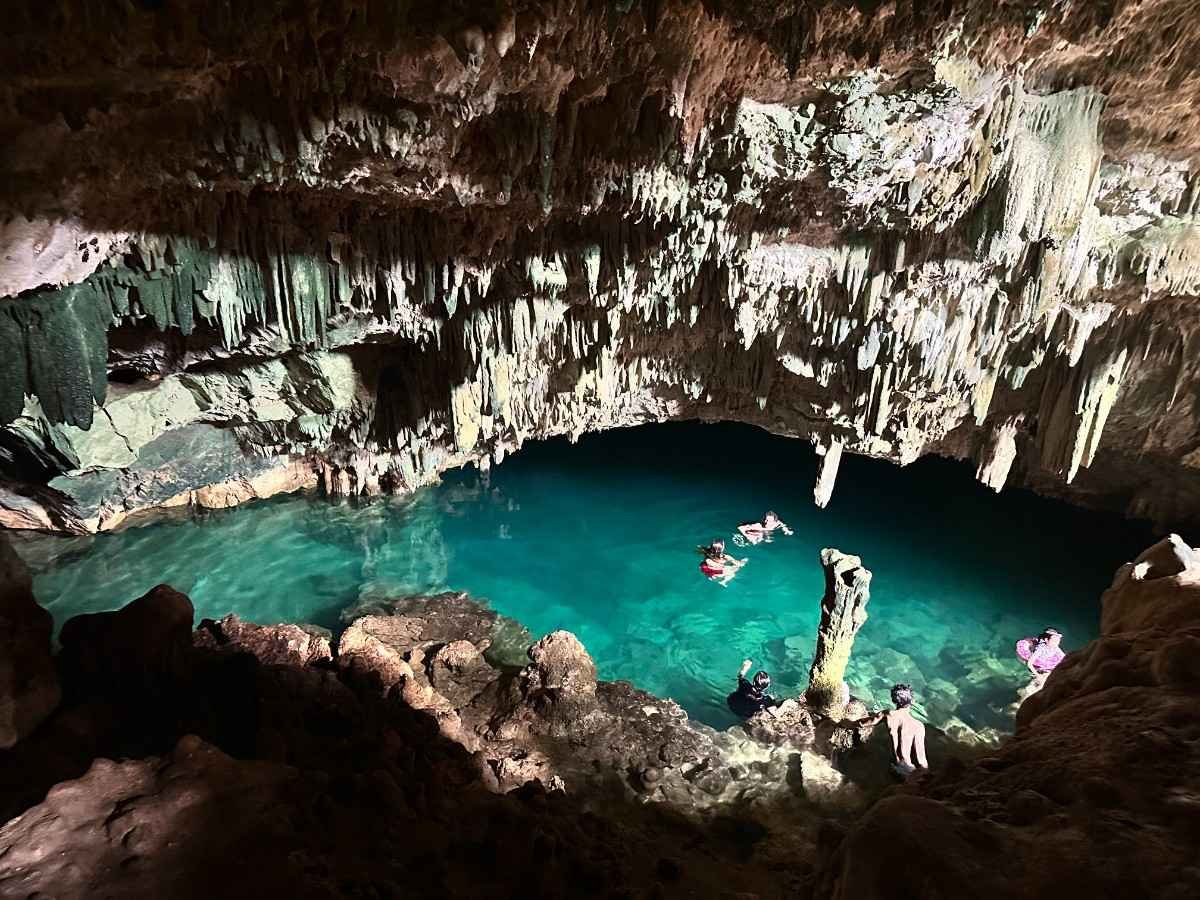 A Local’s Guide to Hidden Indonesia Adventures 5 Swimmers in the crystal-clear water of Rangko Cave, surrounded by stalactites and rocks inside the underground cave.Rangko Cave tour