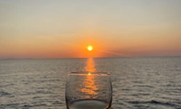 Romantic sunset over the ocean with a glass of wine, capturing a perfect evening view.