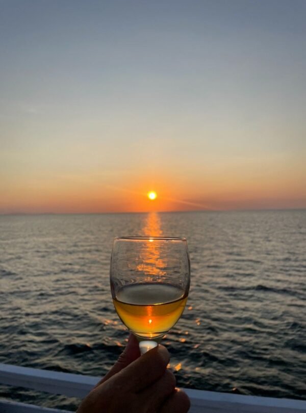 Romantic sunset over the ocean with a glass of wine, capturing a perfect evening view.
