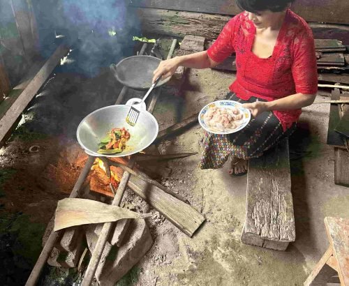 Young woman cooking traditional Indonesian food in a village setting in Flores
