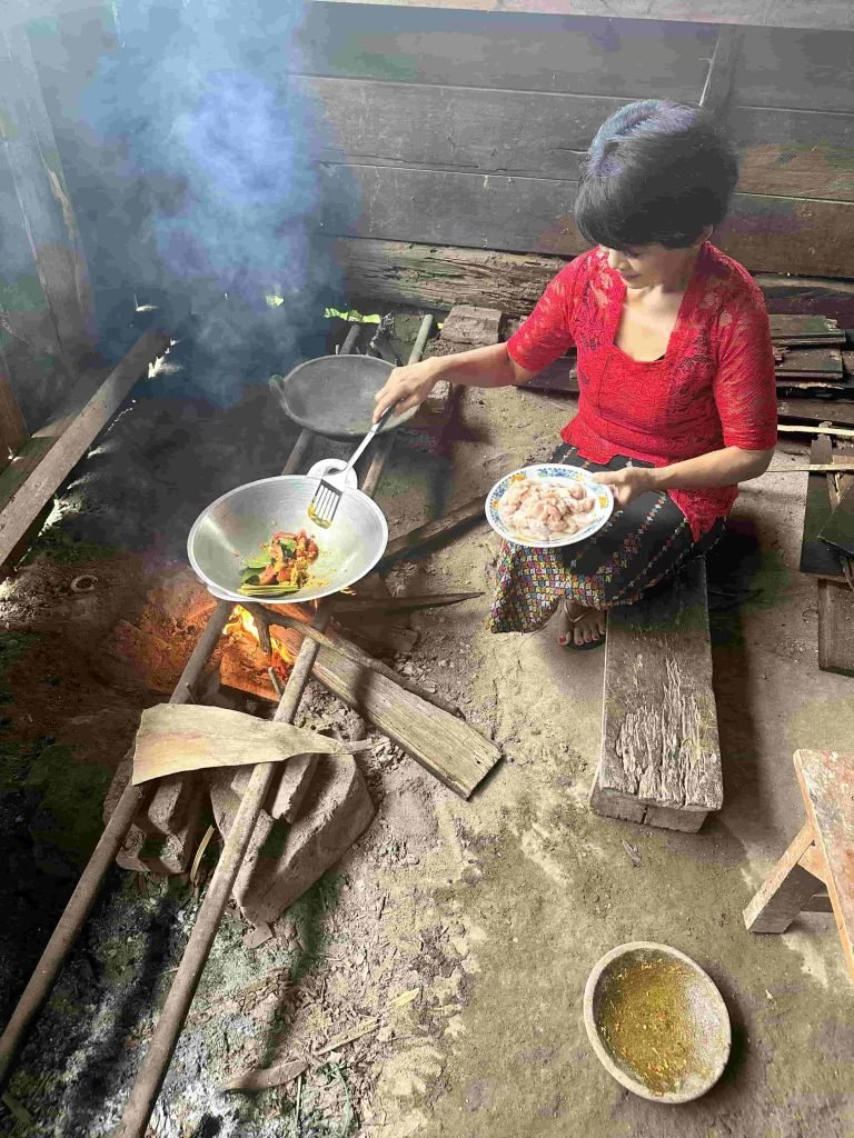 Young woman cooking traditional Indonesian food in a village setting in Flores