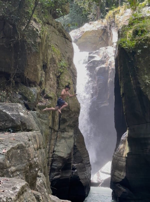 People swimming and relaxing in the clear, tranquil pools of Cunca Wulang Waterfall.