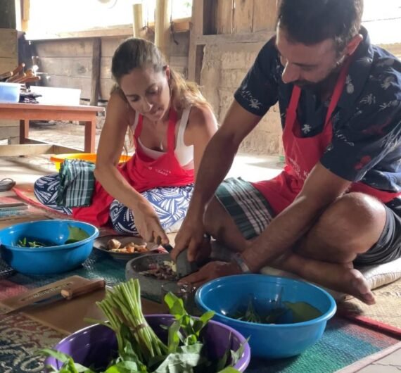 Ina's Cooking Class 3 A group of people smiling and enjoying a homemade meal together in a village setting.