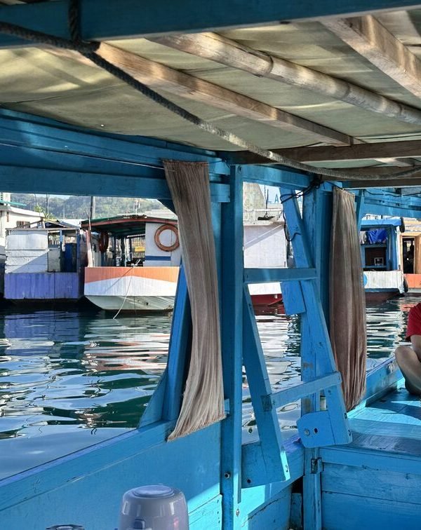Guest relaxing on a traditional blue wooden boat during a Labuan Bajo tour