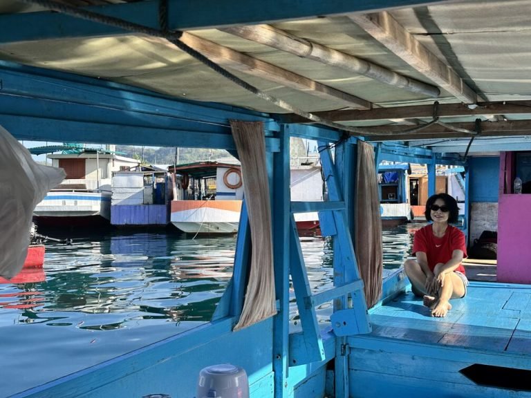 Guest relaxing on a traditional blue wooden boat during a Labuan Bajo tour