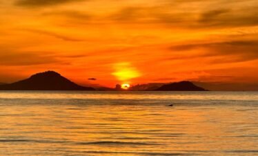 Labuan Bajo snorkeling trip ,Sunset over Labuan Bajo harbor with fishing boats bobbing in the ocean, vibrant and scenic.