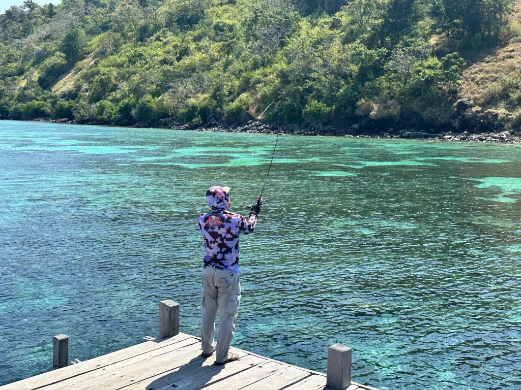 Local fisherman casting a net from a traditional wooden boat in Labuan Bajo