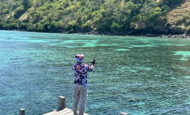 Local fisherman casting a net from a traditional wooden boat in Labuan Bajo