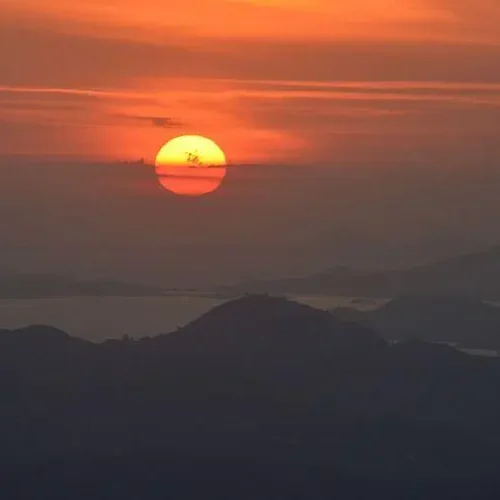 Tourists watching sunset from Puncak Watu Api viewpoint deck in Flores