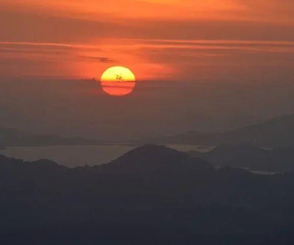 Tourists watching sunset from Puncak Watu Api viewpoint deck in Flores