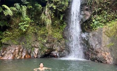 A scenic view of lush waterfalls, including Cunca Wulang and Cunca Pleies, amidst green tropical landscape in Flores.