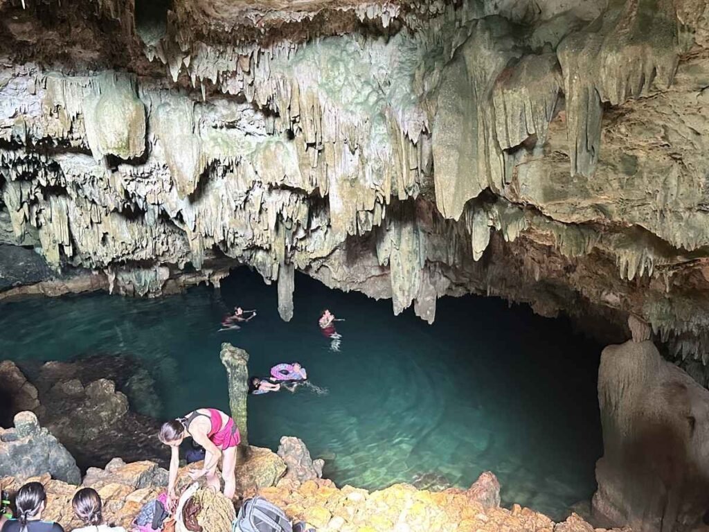 Discover the Magic of Indonesia: Top Cultural & Nature Escapes 6 People swimming in Rangko Cave and relaxing in a natural pool inside a large cave with stalactites.