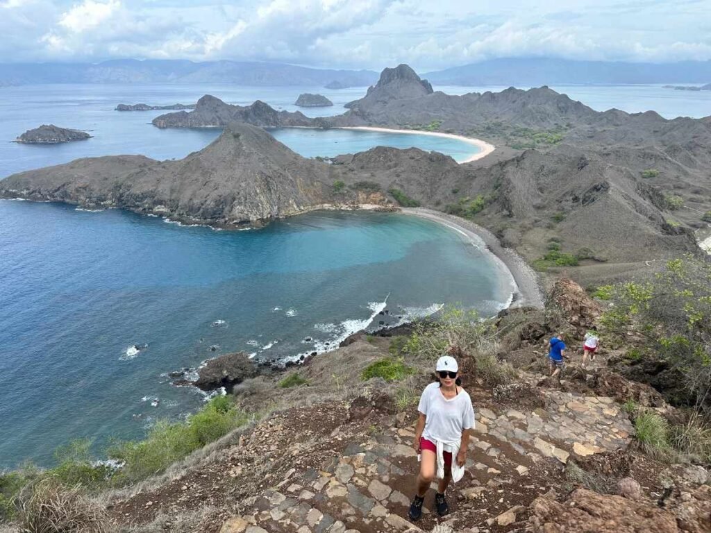island hopping ,Woman hiking on a rocky trail with panoramic mountain and ocean views.