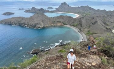island hopping ,Woman hiking on a rocky trail with panoramic mountain and ocean views.