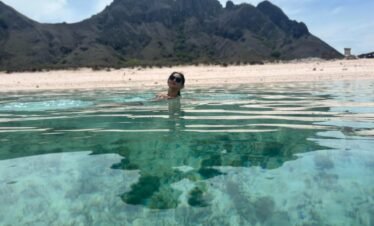 : Woman swimming in crystal-clear waters at Pink Beach Komodo