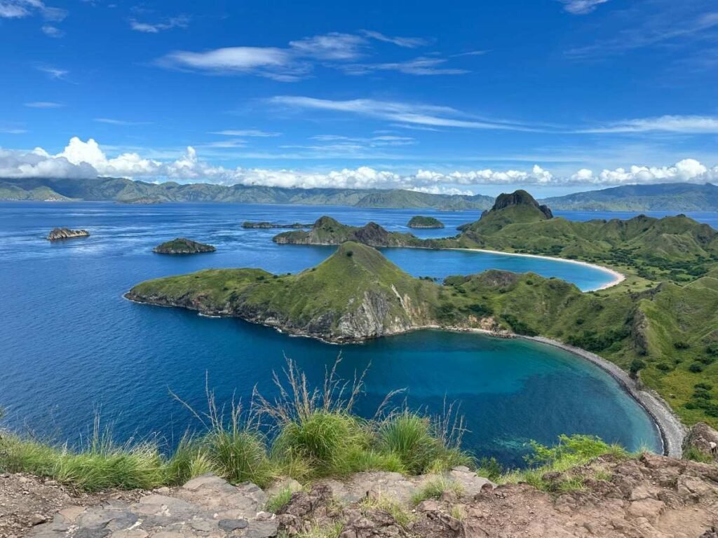 Home 32 Scenic view of Flores islands with turquoise bays and lush green hills under a clear blue sky.