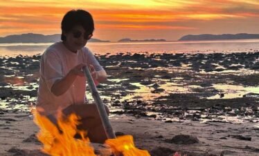 Person sitting beside a bonfire on Rangko beach during sunset ,Rangko Village Sunset Tour