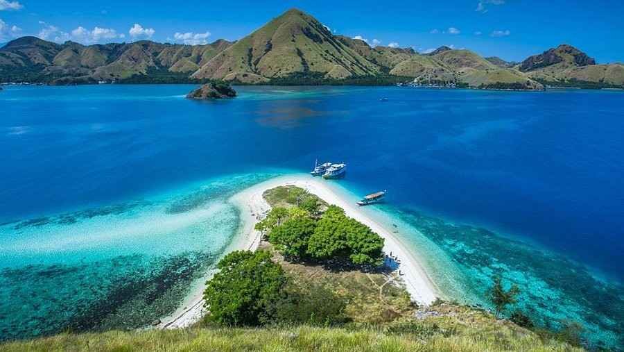 Boat anchored near small tropical island with turquoise water near Labuan Bajo