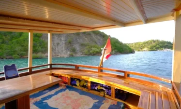 Luxury liveaboard cabin interior with ocean view and tropical island mountains in Komodo