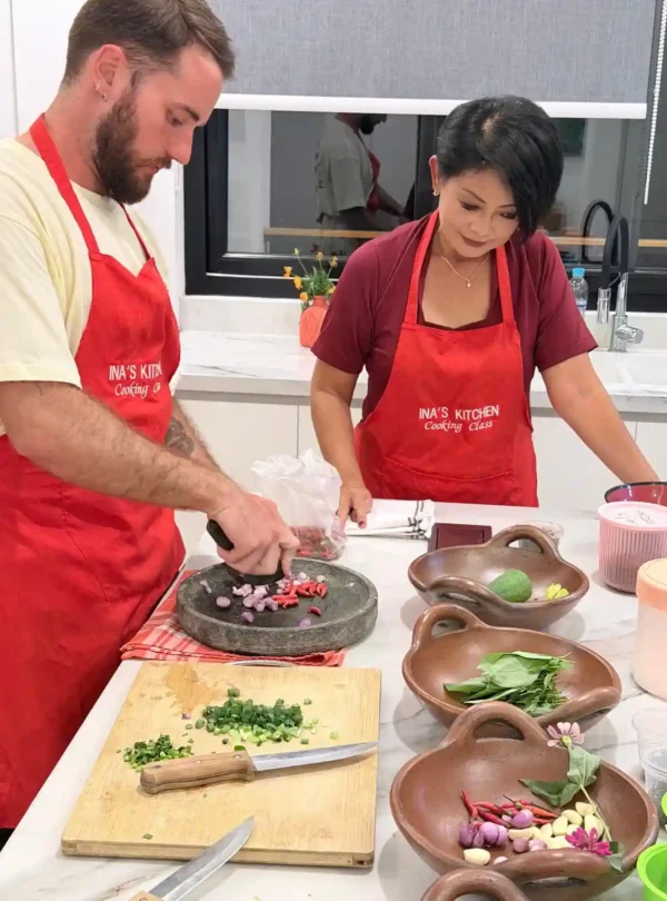 Cooking class participant preparing fresh Indonesian herbs, garlic, chili and shallots in Labuan Bajo.