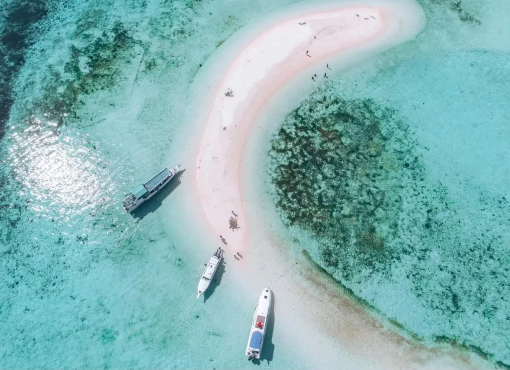 Private speedboats anchored beside a white sandbar in the turquoise waters of Komodo