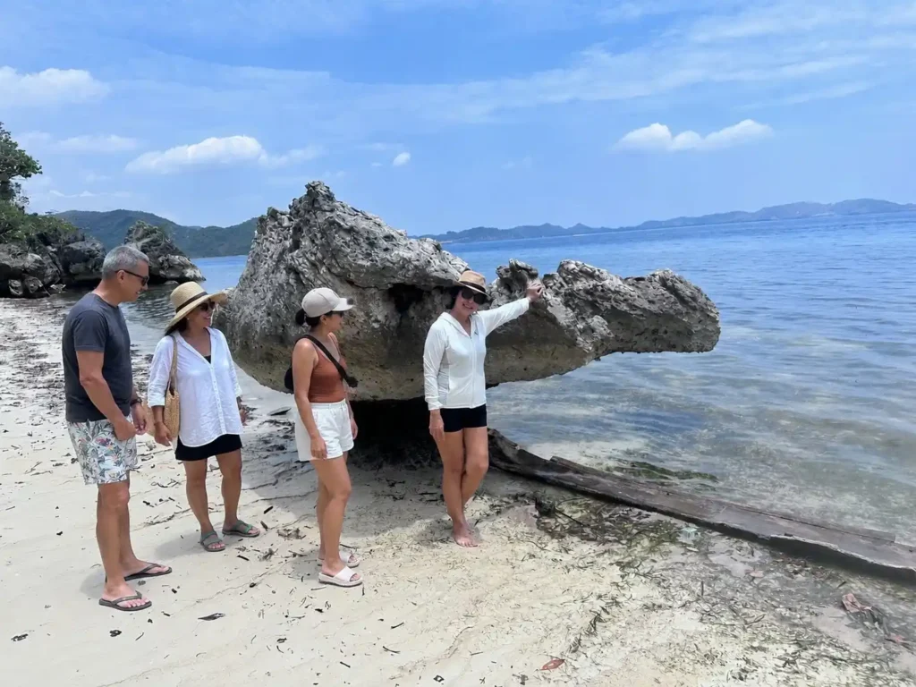 Travelers exploring a natural coastal rock formation in Labuan Bajo