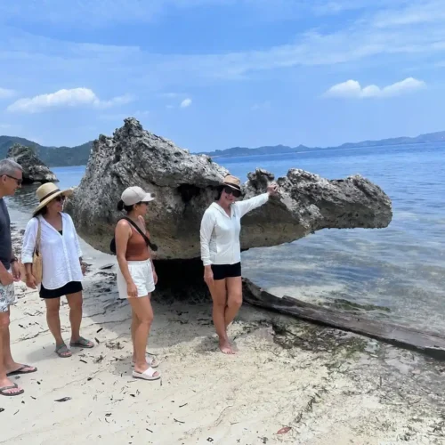 Travelers exploring a natural coastal rock formation in Labuan Bajo