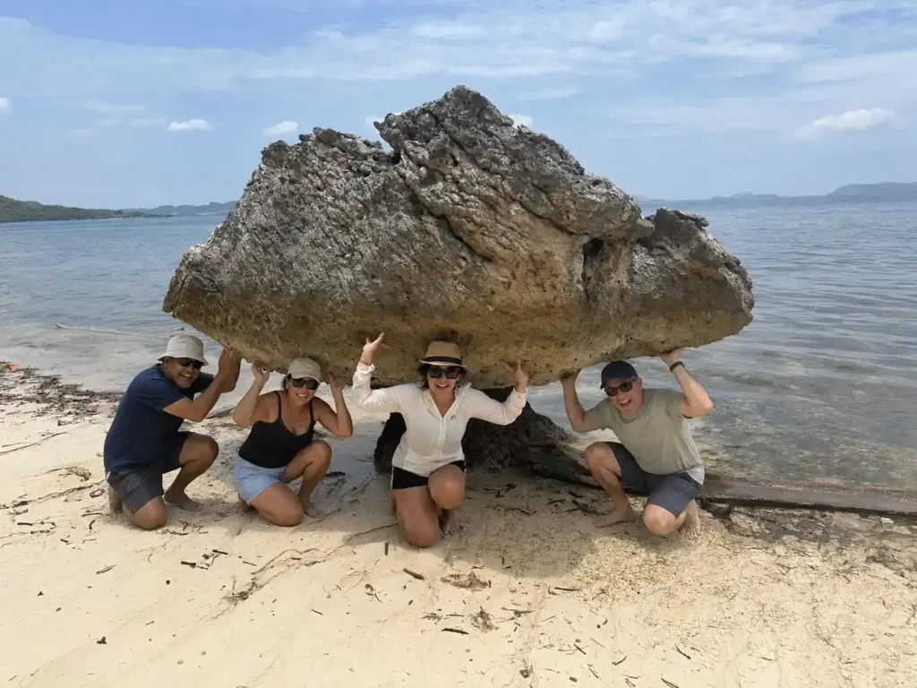 Travelers posing beneath a natural rock formation on a Labuan Bajo island