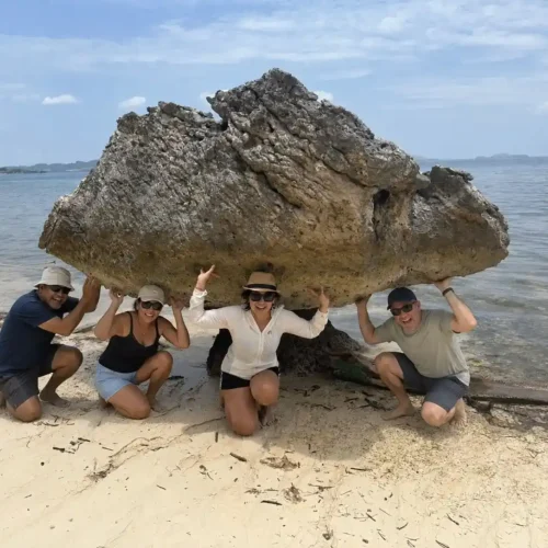 Travelers posing beneath a natural rock formation on a Labuan Bajo island