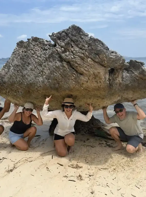 Travelers posing beneath a natural rock formation on a Labuan Bajo island