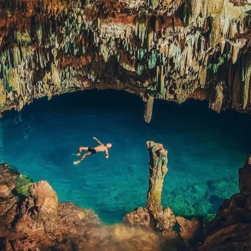 Traveler swimming in the natural saltwater pool inside Rangko Cave near Labuan Bajo